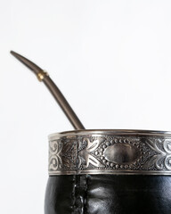 Traditional mate cup made from gourd covered with black leather and smooth metal rim, isolated on white background. Artisan South American drink container, product photo with copy space.