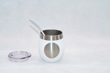 White stainless steel mate cup with lid isolated on white background. Modern reusable container for traditional South American drink, clean product photography with copy space.