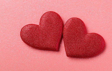 Fototapeta premium two red hearts on a pink glittery background with copy space for a valentine's day celebration, a love concept. 
