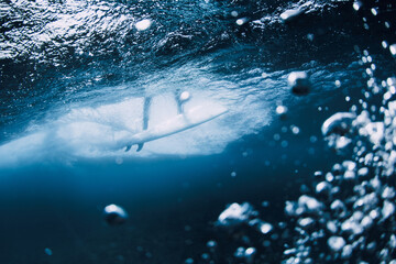Dynamic underwater surfing scene with bubbles and powerful ocean wave.