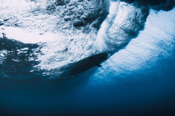 Surfer carving inside powerful wave, underwater perspective of ocean force and extreme sport.