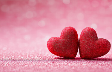 Obraz premium two red hearts on a pink glittery background with copy space for a valentine's day celebration, a love concept. 