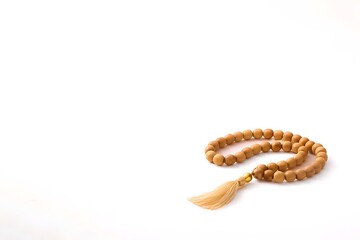 Obraz premium Wooden prayer beads with a tassel arranged on a minimalist white background.