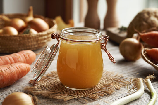 Chicken soup or bone broth in a glass jar on a wooden table