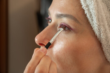 Woman blending eyeshadow with a makeup brush on her face.
Beauty and skincare routine concept. Professional makeup application, cosmetics, self-care, and personal grooming. Close-up portrait.