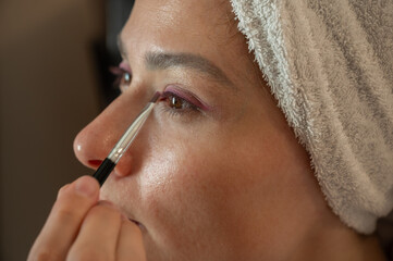 Woman blending eyeshadow with a makeup brush on her face.
Beauty and skincare routine concept. Professional makeup application, cosmetics, self-care, and personal grooming. Close-up portrait.