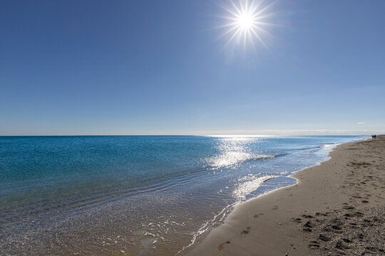 people in distance walking along the shore at the mediterranean in andalusia on the costa del sol spain