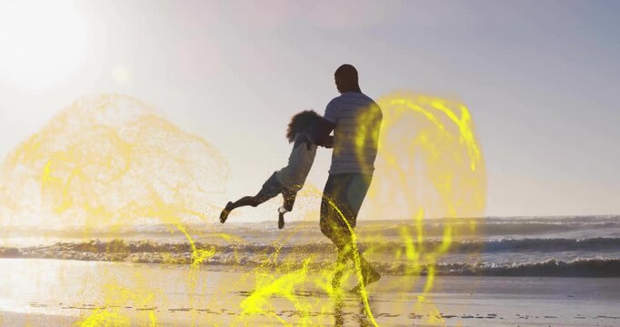 Man gripping daughter's forearms swinging on sunset beach featuring AR rings spiraling for bonding