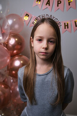 Naklejka premium Sad birthday girl pose with balloons and banners in party room on her specital day
