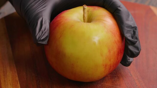 A metal apple corer is pushed through the center of a fresh red apple to remove the core and seeds. Close-up of a kitchen gadget preparing a healthy fruit for baking or a snack