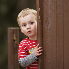 Is the coast clear? A little boy peeks out from behind a play structure.