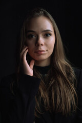 Naklejka premium Intimate Low Key Portrait of Young Woman Touching Face with Soft Natural Window Light and Deep Shadows Creating Emotional Cinematic Mood