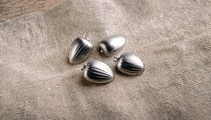 Three Perfectly Uniform Silver Strawberry Seeds Artfully Arranged On A Textured Linen Fabric Surface