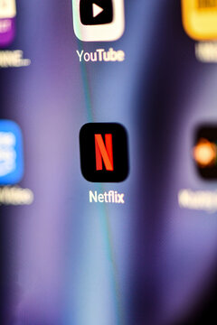 Macro shot of a smartphone screen displaying the Netflix and YouTube app icons. The image captures the vibrant digital interface and the global reach of streaming entertainment media.