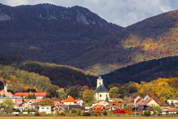 Fototapeta premium Classic Church Tower Rising Above Autumn Village Forest