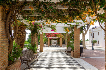 Obraz premium Charming Mediterranean Pergola with Bougainvillea Flowers and Checkerboard Path in Maro Village near Nerja Andalusia Spain