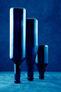 Still life with upside down bottles on a table with a blue background