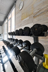 Racked dumbbells organized on stands ready for strength training in fitness center