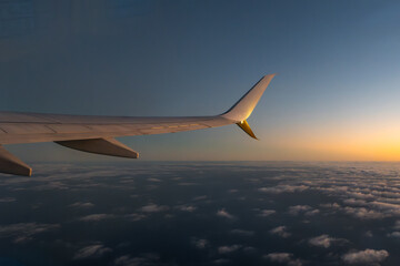 Fototapeta premium view from airplane window. sunset over the clouds