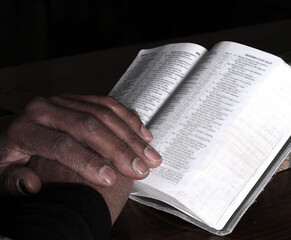Fototapeta premium praying to god with hands showing his religious faith with God Caribbean man praying with black background with people stock photo stock image