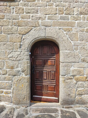 A rustic wooden door set within a massive stone wall, showcasing texture and traditional craftsmanship.