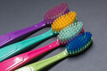 Colorful toothbrushes arranged in a row on a dark background showing different bristle shapes and colors