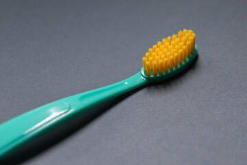Bright green toothbrush with yellow bristles on a gray background