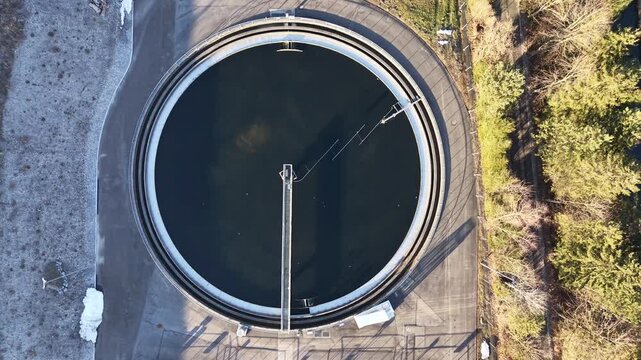 Top-down aerial footage pulling up from a circular water treatment clarifier, showing industrial wastewater processing and environmental infrastructure.