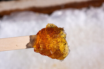 Close-up of traditional maple taffy rolled on a wooden stick