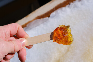Hand holding a fresh maple taffy stick in winter