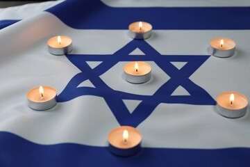Holocaust Remembrance Day. Burning candles on flag of Israel, closeup