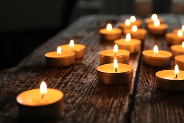 Holocaust Remembrance Day. Burning candles on wooden table, closeup