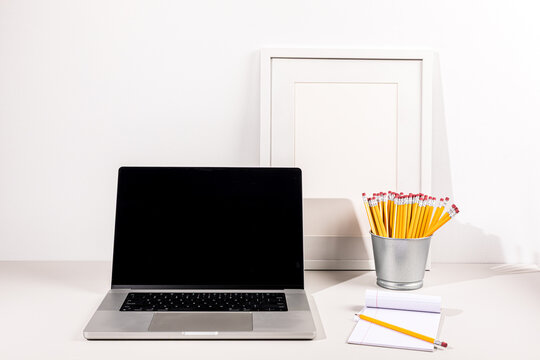 Laptop on gray surface with white wall