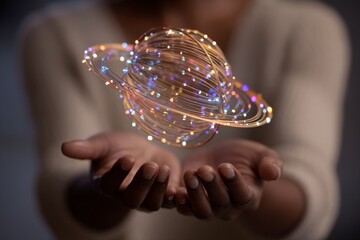 A person holds a small glowing planet made of lights that spin gently above open hands in a dark studio.