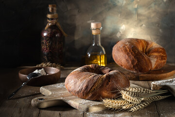 Fresh wheat bread and ears of wheat on a rustic table