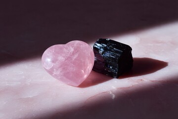 gemstone still life, simple gemstone still life rose quartz heart and black tourmaline on pink marble, with soft natural light from above