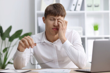 Naklejka premium Work fatigue. Overwhelmed businessman with glasses suffering at table in office