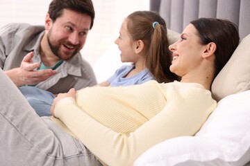 Obraz premium Pregnant woman, her husband and daughter on bed at home