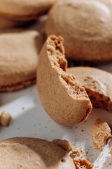 Bitten peanut macaron closeup with crumbs on white plate, shallow depth of field