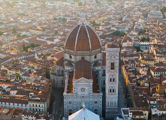 Obraz premium Aerial view of Florence historic city center at sunrise, highlighting the Duomo and dense urban fabric illuminated by soft golden morning light in Italy