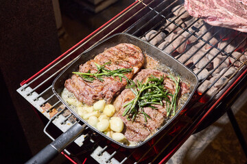 barbecue party, close-up image of grilling steaks, the meat is stewed in butter with garlic and thyme, spiking pieces of meat on the grill, various vegetables, lots of smoke