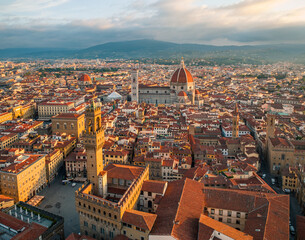 Fototapeta premium Aerial view of Florence city skyline at sunrise with the Duomo dominating the historic center. Soft golden morning light illuminates rooftops and Renaissance architecture in Tuscany, Italy