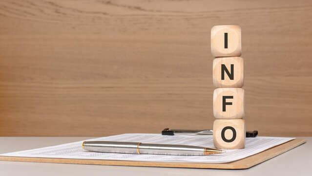 Wooden blocks spelling INFO stacked on documents with pen on desk information concept