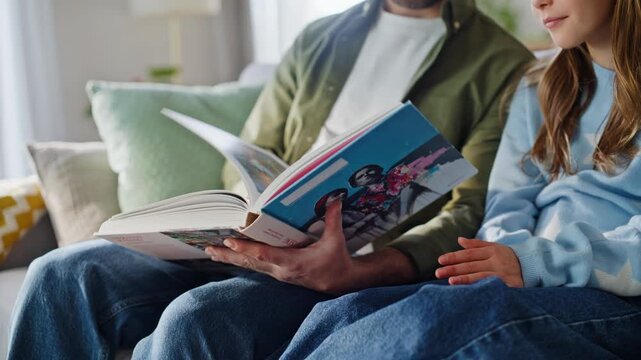Father hands flipping pages looking interesting story to adorable daughter.