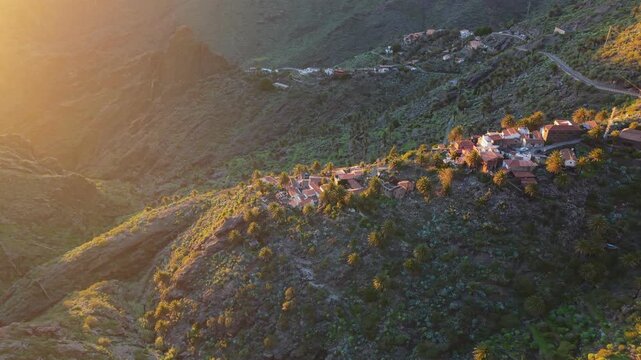 Aerial view of Masca village, perched on mountain ridge in Teno Rural Park. Dramatic Masca valley landscape, winding roads, and traditional architecture at sunset. Tenerife, Canary Islands, Spain