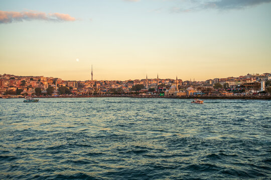 Golden-hour view across Bosphorus toward Uskudar waterfront, Istanbul, Turkey with Camlica Tower left, Mihrimah Sultan Mosque and Semsi Ahmet Pasha Mosque right against clear sky
