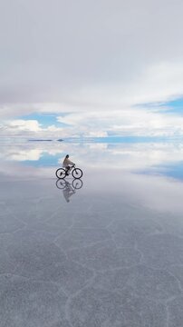 A cyclist rides across the expansive Salar de Uyuni in Bolivia, capturing the surreal beauty of the world's largest salt flat