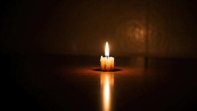 Solitary Candle Flame Illuminating Deep Darkness with Warm