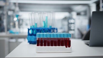 Close up of small glass flasks containing red blood samples on laboratory workbench. Sanguine fluid specimens prepared for clinical diagnostic testing in sterile environment