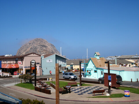 Morro Rock towering over the coastal town with colorful buildings and a sunny sky